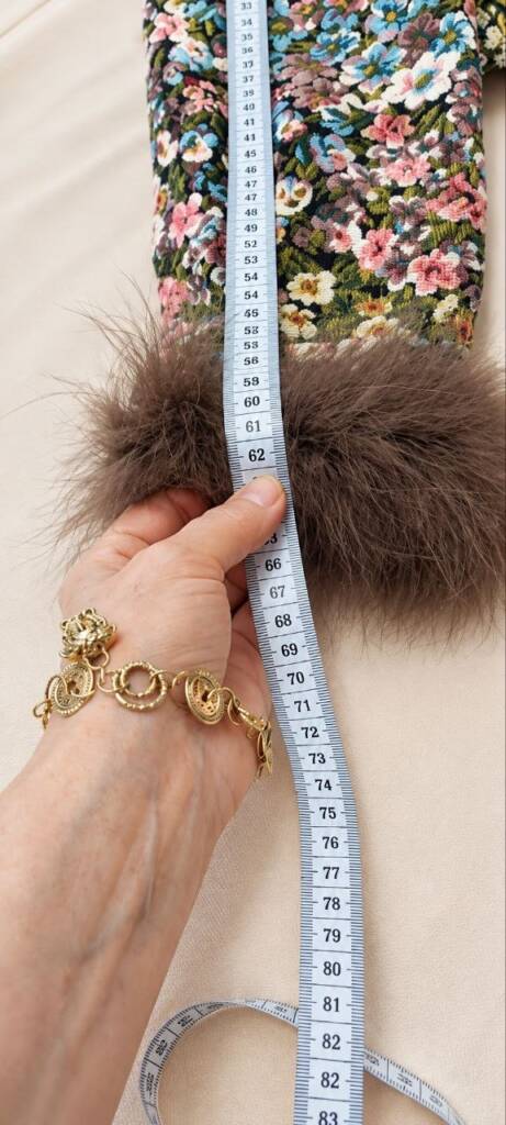 Hands measuring a couture jacket in the atelier