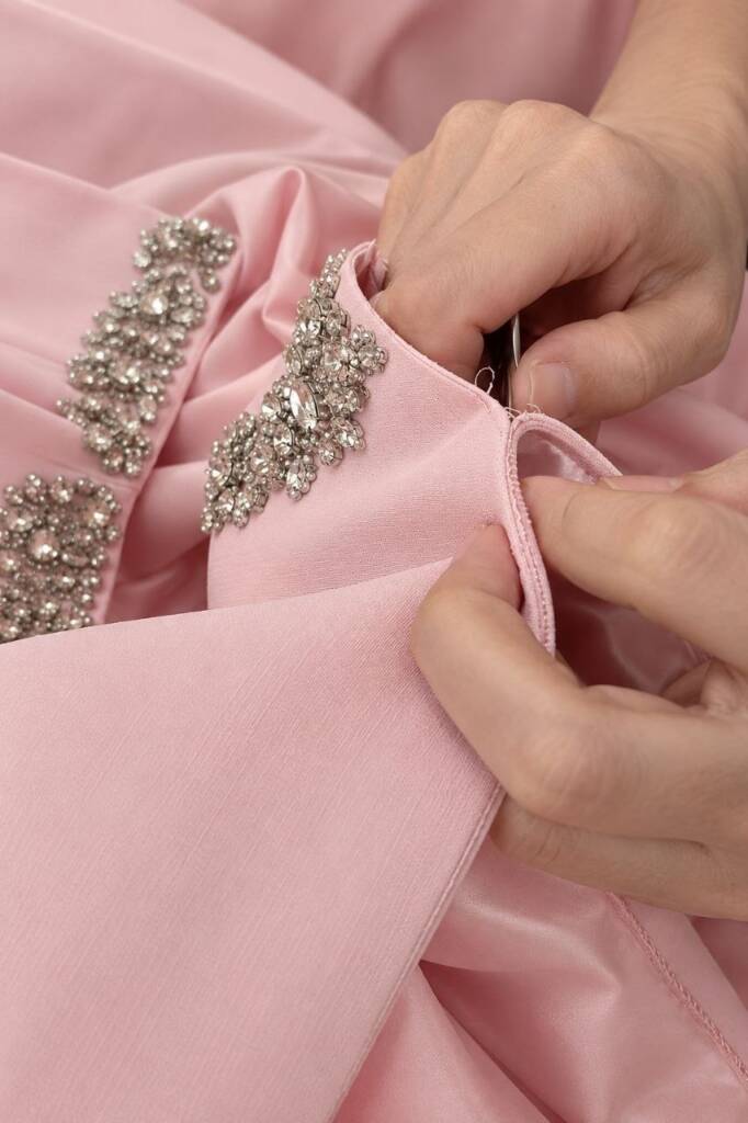 Hands re-setting crystals on a couture sleeve